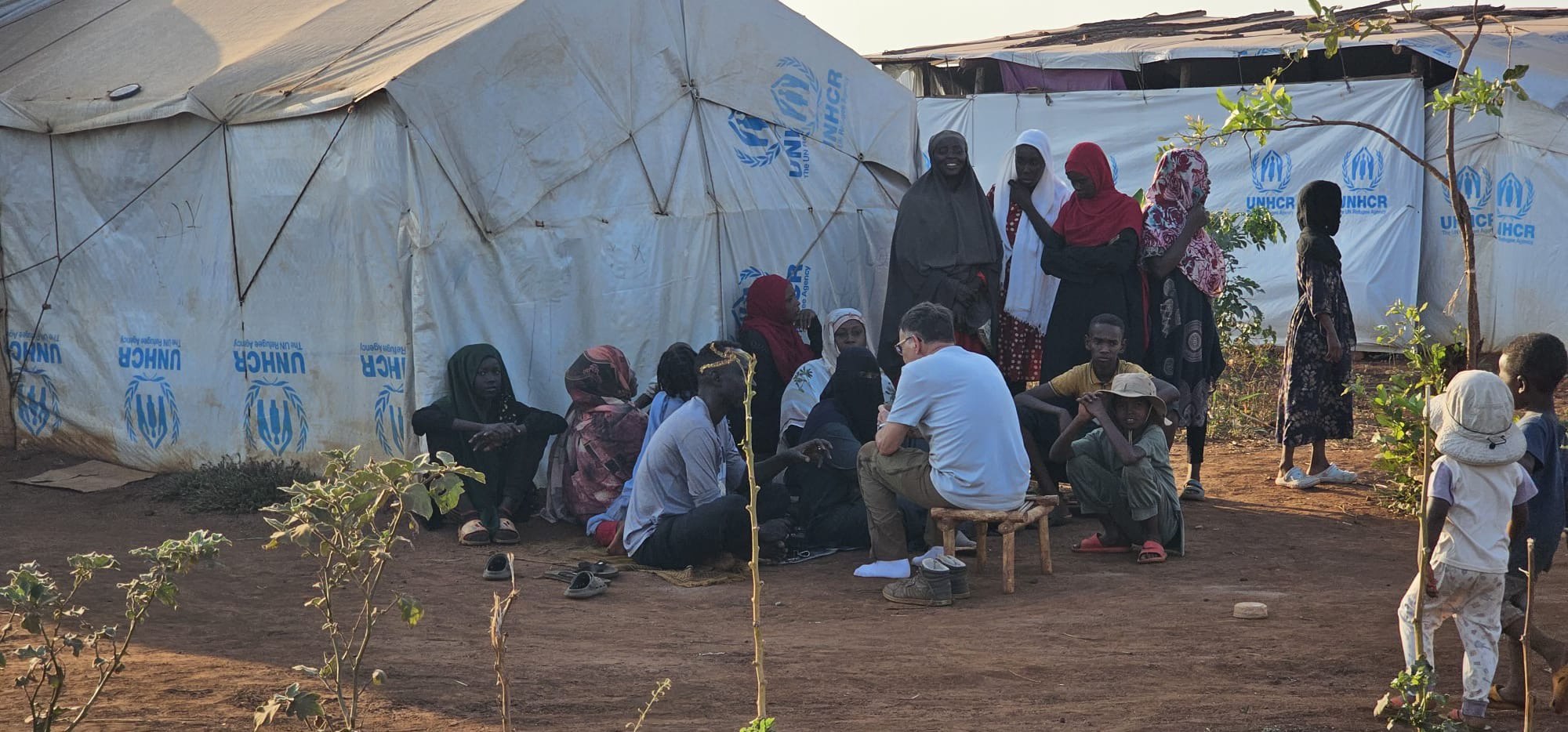 Aid worker speaks with refugees in a UNHCR tent in Uganda.