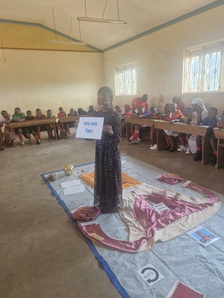 Girl in classroom presenting a sign reading "400,000 Eggs," illustrating a lesson.