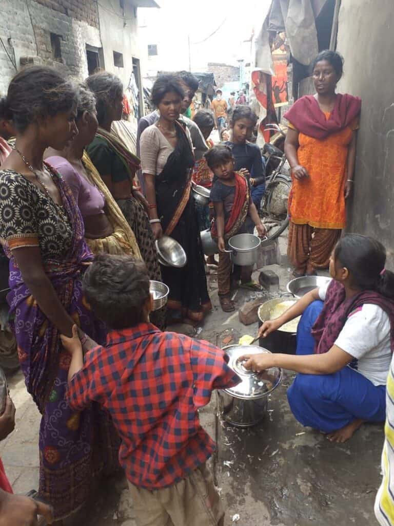 Frauen und Kinder in einem Slum erhalten Nahrung; Armut, Hungerhilfe, Gemeinschaftsküche