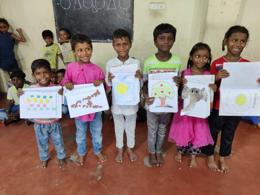 Glückliche Kinder zeigen stolz ihre farbenfrohen Kunstwerke, darunter Zeichnungen einer Sonne, eines Baums und eines Elefanten.