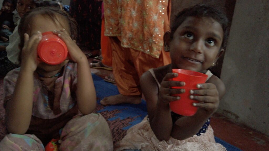 Zwei junge Mädchen trinken aus roten Tassen. Kinderarmut, Hilfe und humanitäre Hilfe.