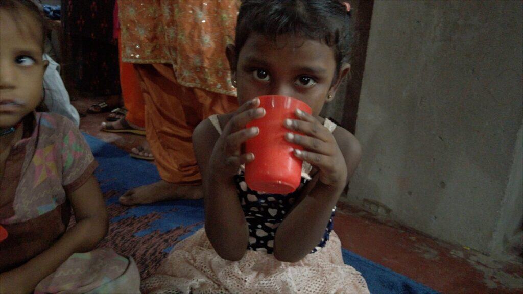 Junges Mädchen trinkt Wasser aus einer roten Tasse
