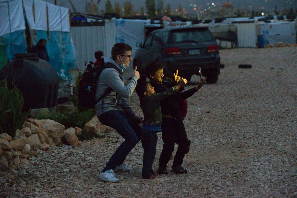 Mann und Kinder machen nachts ein Selfie in einem Flüchtlingslager.