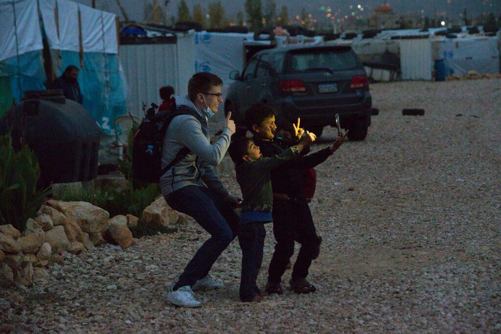Mann und Kinder machen nachts ein Selfie in einem Flüchtlingslager.