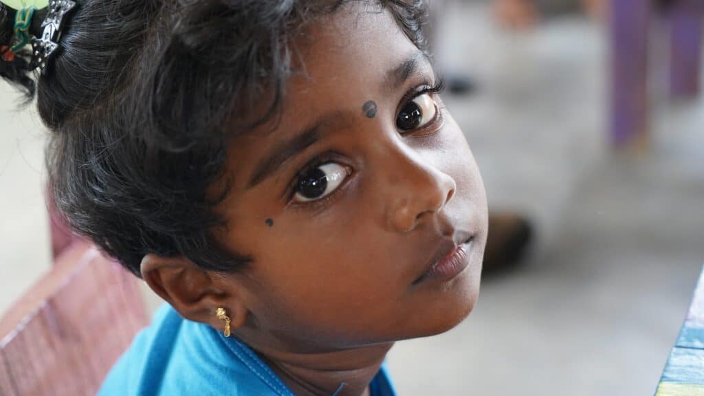 Nahaufnahmeporträt eines jungen Mädchens mit dunklem Haar und ausdrucksstarken Augen.