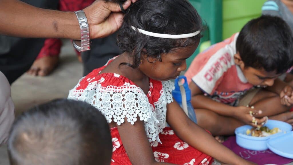 Mädchen im roten Kleid bekommt Haarband, Kinder essen.