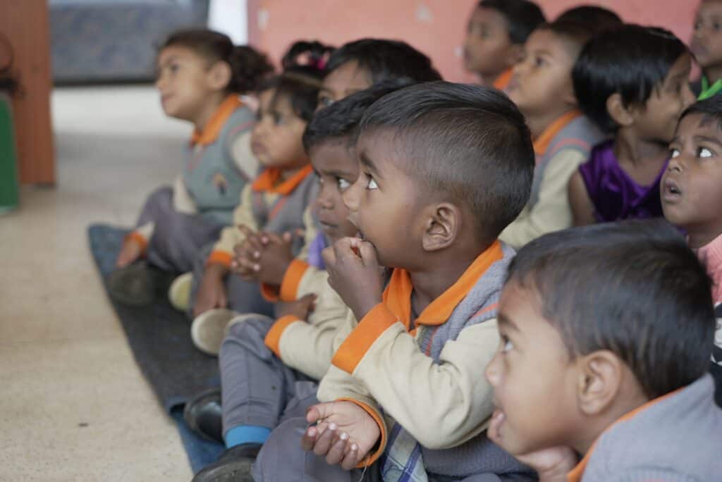 Eine Gruppe aufmerksamer Vorschulkinder sitzt auf dem Boden und hört aufmerksam zu.