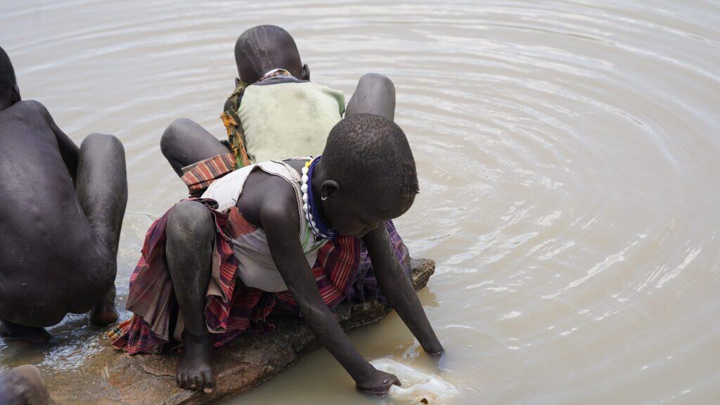 Kinder in Afrika holen Wasser aus einem Teich.
