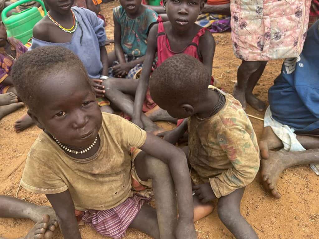 Unterernährte Kinder sitzen zusammen auf dem Boden und zeigen die Auswirkungen von Hunger und Hunger.