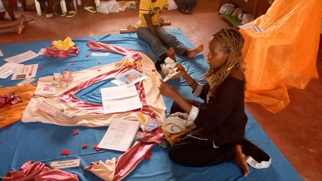 Eine Frau leitet eine Aufklärungssitzung zum Thema Menstruation und stellt Hygieneprodukte und Aufklärungsmaterialien vor.