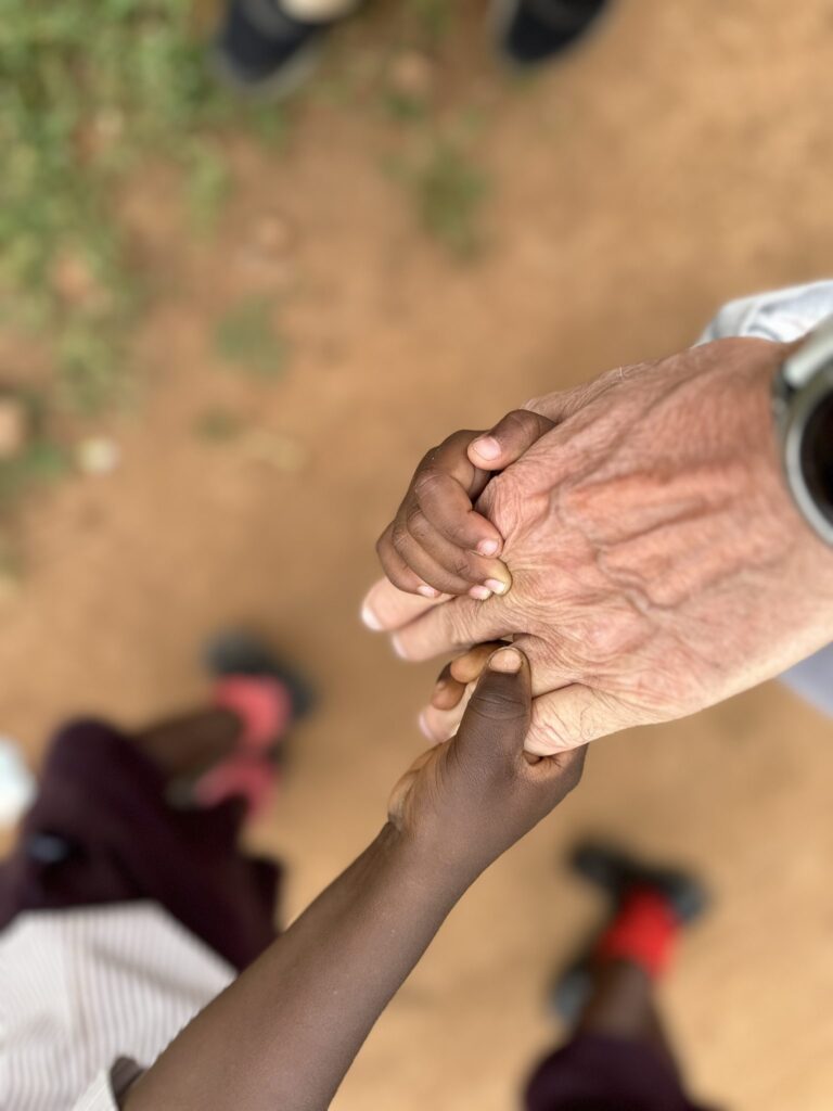 Nahaufnahme der Hand eines Erwachsenen, der die Hände zweier Kinder hält. Zeigt die Verbindung zwischen den Generationen.