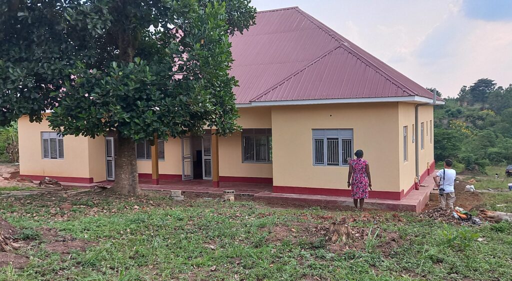 Neu gebautes Haus im ländlichen Uganda mit Menschen, die den Bau inspizieren