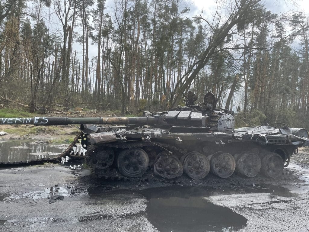 Beschädigter russischer Panzer T-72 in einem schlammigen Wald. Auf dem Geschützrohr steht das Graffiti „VERINES“.