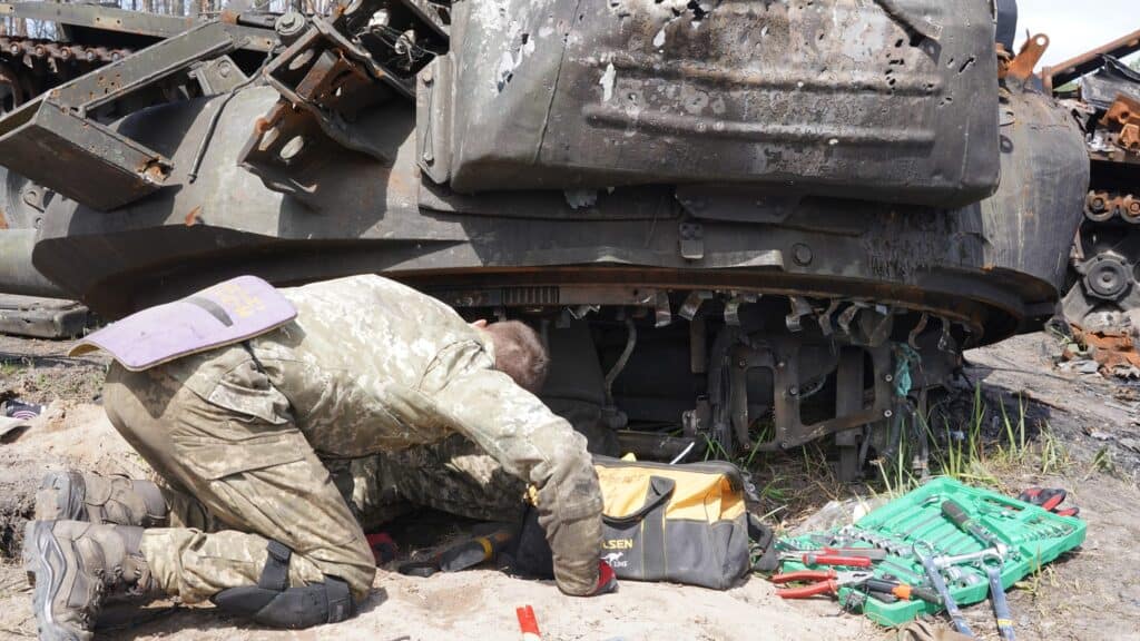 Ein Soldat repariert einen beschädigten Militärpanzer mit Werkzeugen aus seinem Werkzeugkasten.
