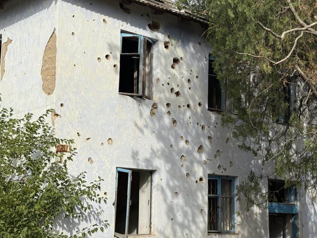 Von Kugeln durchsiebte Gebäudefassade mit beschädigten Fenstern in der Ukraine. Kriegsschäden.