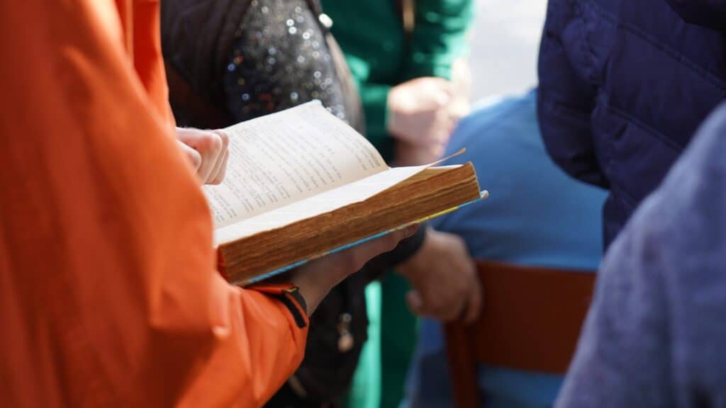 Person, die in einer Gruppe eine abgenutzte Bibel liest.