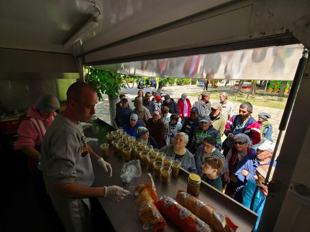 Freiwillige servieren einer Menschenschlange im Freien heiße Suppe und Brot. Wohltätigkeitsorganisation „Food Bank“.