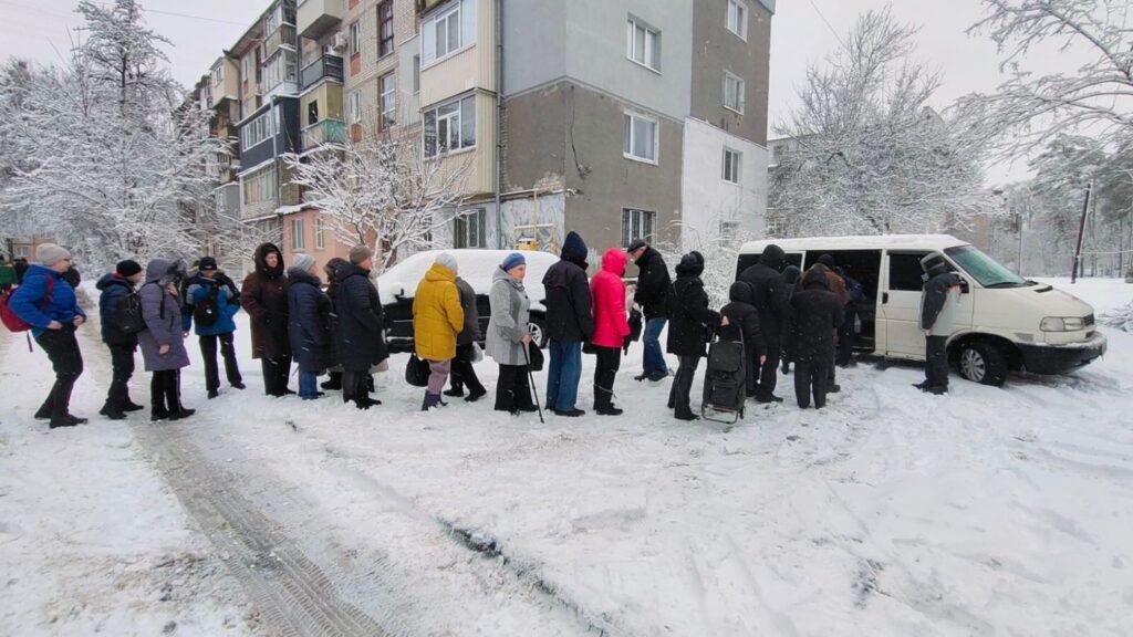 Menschen steigen bei Schnee in einen Lieferwagen. Evakuierung im Winter.