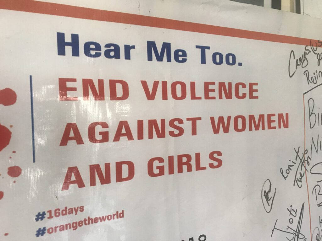 Schild mit der Aufschrift „Hört mich auch an. Schluss mit Gewalt gegen Frauen und Mädchen“ mit Unterschriften. #16days #orangetheworld