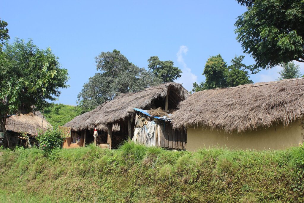 Strohgedeckte Hütten im ländlichen Nepal, die traditionelle Architektur zeigen.