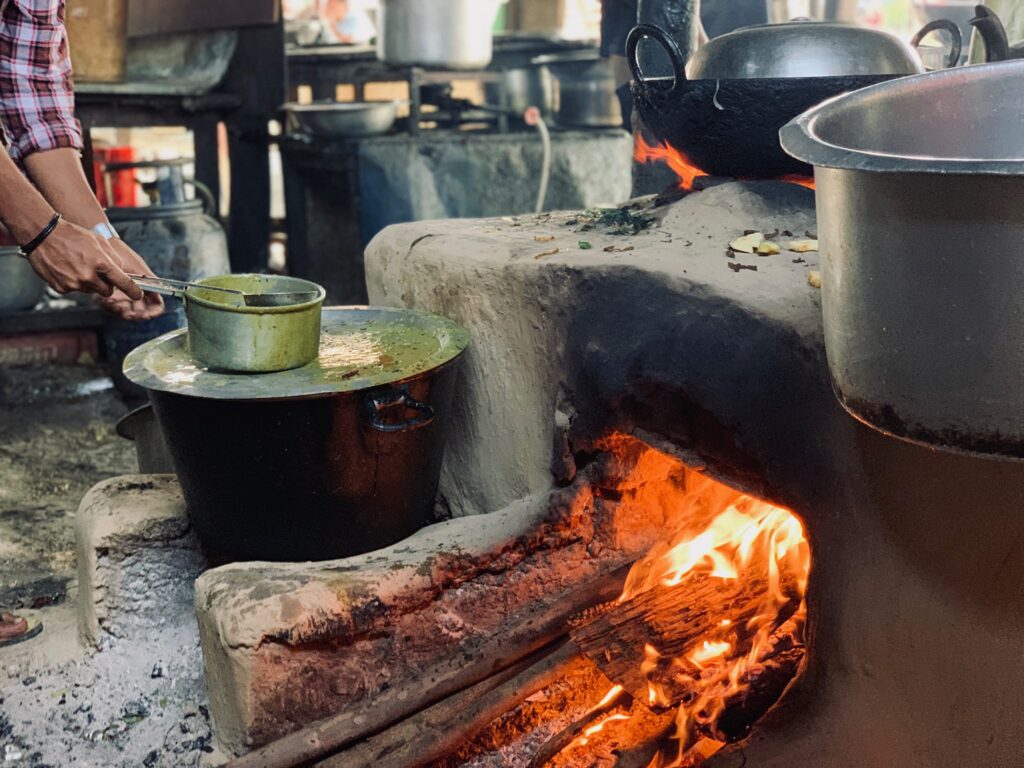 Person, die in einer rustikalen Küche traditionelles Essen über offenem Feuer kocht.