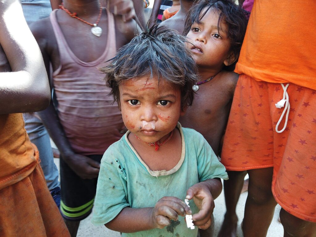 Kleines Kind mit schmutzigem Gesicht, umgeben von anderen Kindern.
