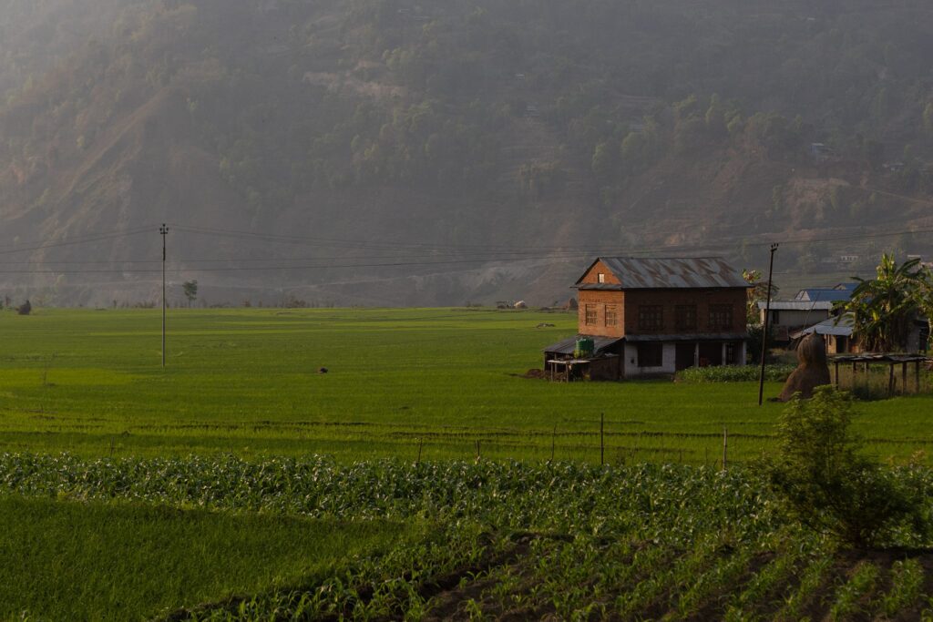 Backsteinhaus auf einer üppig grünen Wiese mit Bergen im Hintergrund.