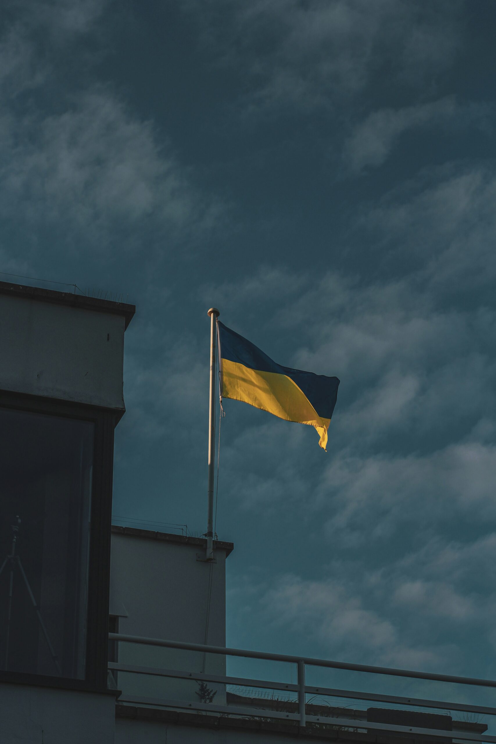 Ukrainische Flagge weht auf einem Gebäudedach unter einem bewölkten Himmel.