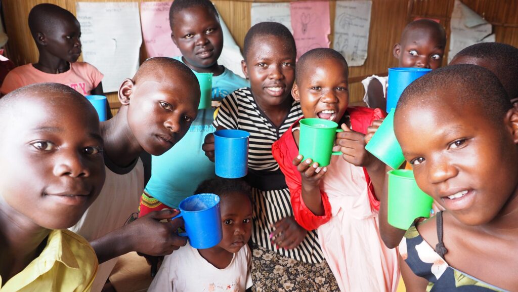 Glückliche afrikanische Kinder genießen nahrhafte Milch in bunten Tassen.