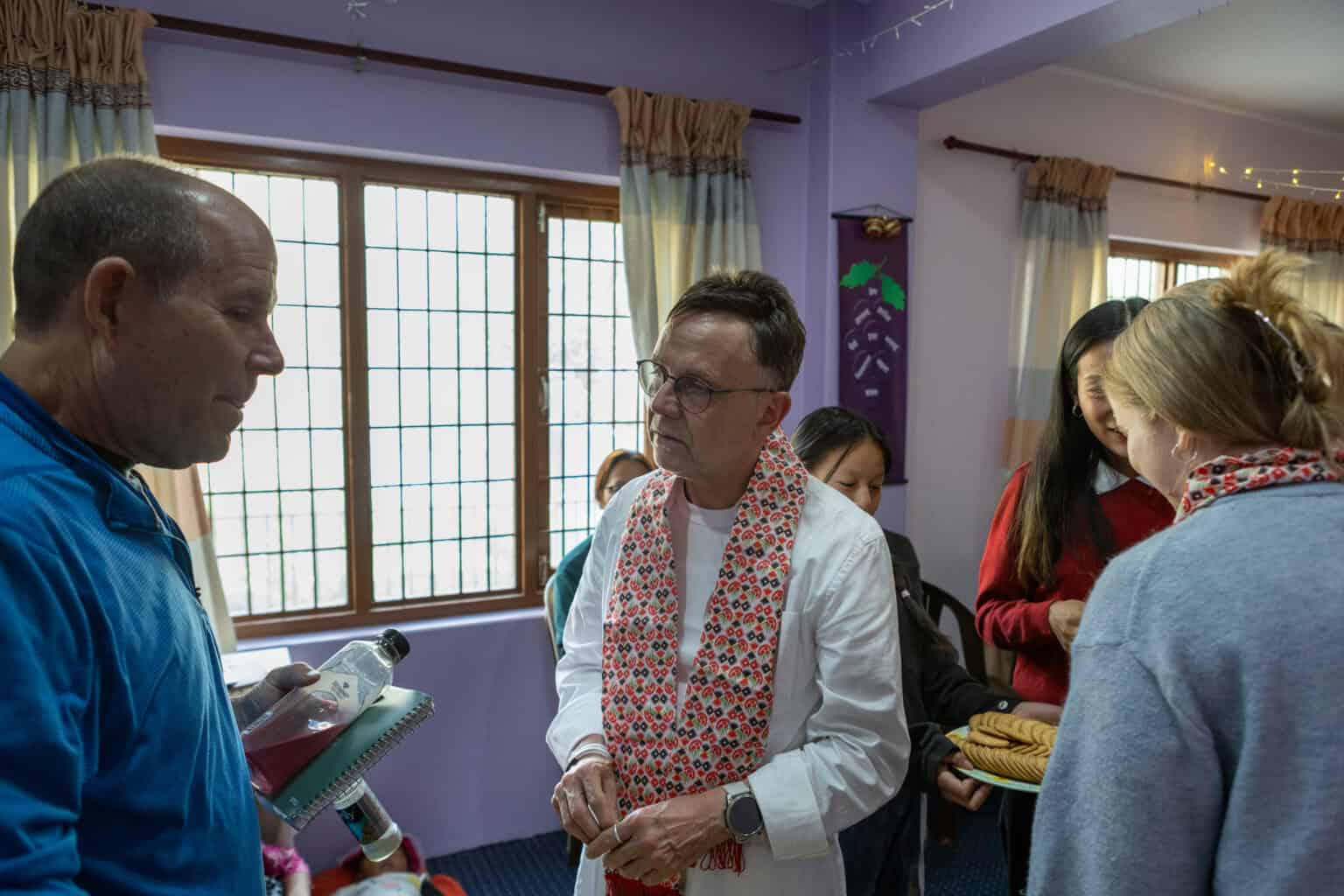 Eine Gruppe von Menschen unterhält sich in einem Innenraum mit traditioneller Dekoration.