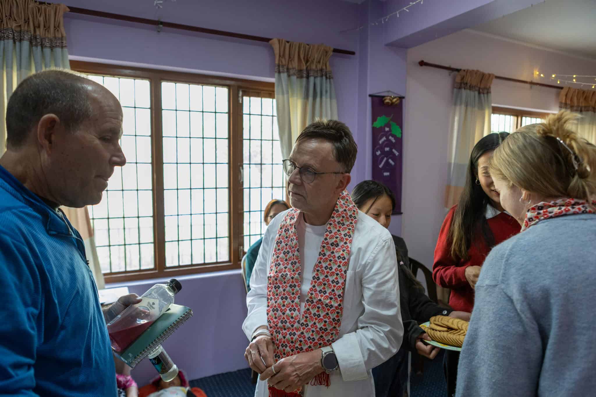 Eine Gruppe von Menschen unterhält sich in einem Innenraum mit traditioneller Dekoration.